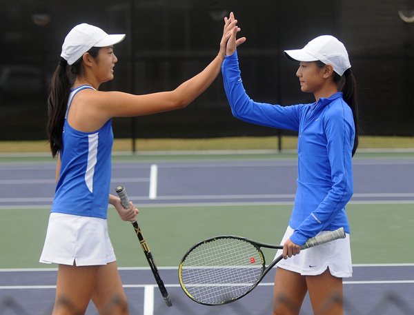 Tiffany Tang, left, and Katherine Tang, of Rogers High, high five on Oct. 9 during the doubles match at the 7A/6A West Conference Tennis Tournament in Fayetteville. 