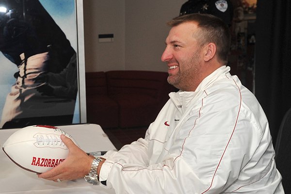 Arkansas coach Bret Bielema signs autographs during the Razorbacks' fan day on Sunday, Aug. 18, 2013 at Bud Walton Arena in Fayetteville. 