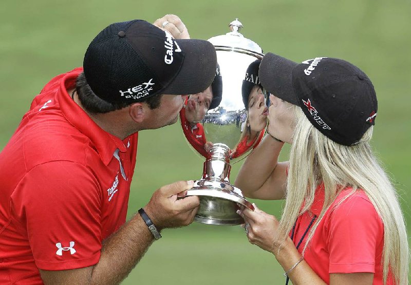 Patrick Reed and his wife and caddy, Justine kiss the Sam Snead trophy after he won the Wyndham Championship golf tournament in a second hole playoff at the Sedgefield Country Club in Greensboro, N.C., Sunday, Aug. 18, 2013. (AP Photo/Bob Leverone)
