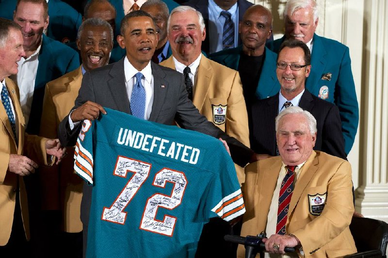 Forty-one years after being the only NFL team to have a perfect season, the 1972 Miami Dolphins finally got to visit the White House. President Barack Obama holds a signed Miami Dolphins football jersey during a ceremony in the East Room of the White House on Tuesday. Hall of Fame coach Don Shula is on the right. 