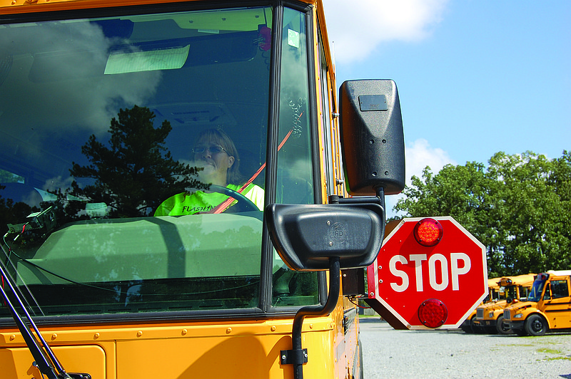 Bryant School District bus driver Cindy Henson comes to a stop and displays a red stop sign on the opening day of school Monday. Henson, who has been driving the big yellow buses for 29 years, is one of the many school-bus drivers in the state taking part in Arkansas’ Flashing Red, Kids Ahead campaign asking motorists to be alert and stop as children get on or off the bus.