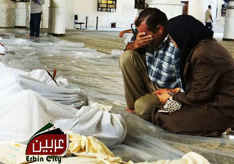 A Syrian man and woman mourn Wednesday over the bodies of victims of a purported poison-gas attack in Arbeen on the outskirts of Damascus. 