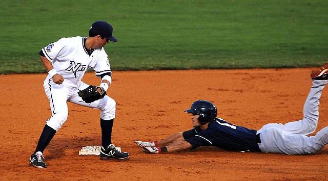 Northwest Arkansas’ Whit Merrifield (left) turns to apply a tag to Arkansas’ Jimmy Swift as he slides into second base Saturday during the Travelers’ 6-5 victory over the Naturals at Arvest Ballpark in Springdale. 