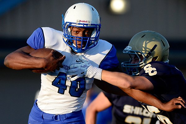 Rogers junior Bryan Grigsby pushes off a tackle attempt from Shiloh Christian senior Kyle Kennedy during the second quarter of their scrimmage on Monday, Aug. 26, 2013, at Champions Stadium in Springdale. <strong><em>Correction: </strong>Bryan Grigsby was previously misidentified. The error has been corrected.</em>