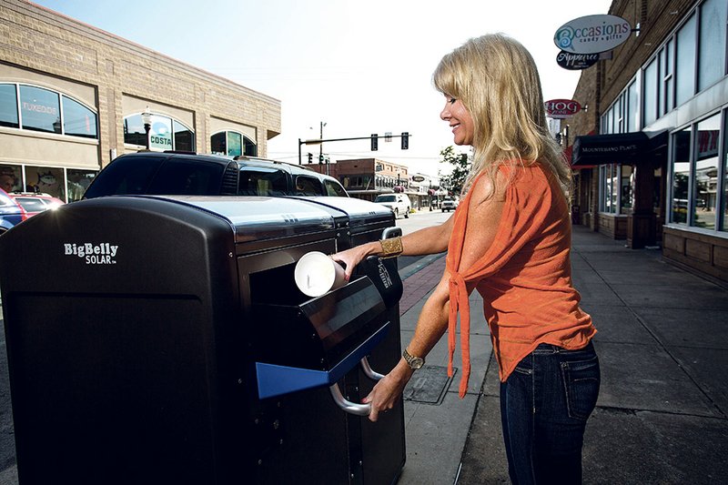 Cindy Hudson, a gemologist at Fletcher Smith’s Jewelers in Conway, utilizes the new BigBelly Solar trash receptacle on Oak Street in the city’s downtown district.