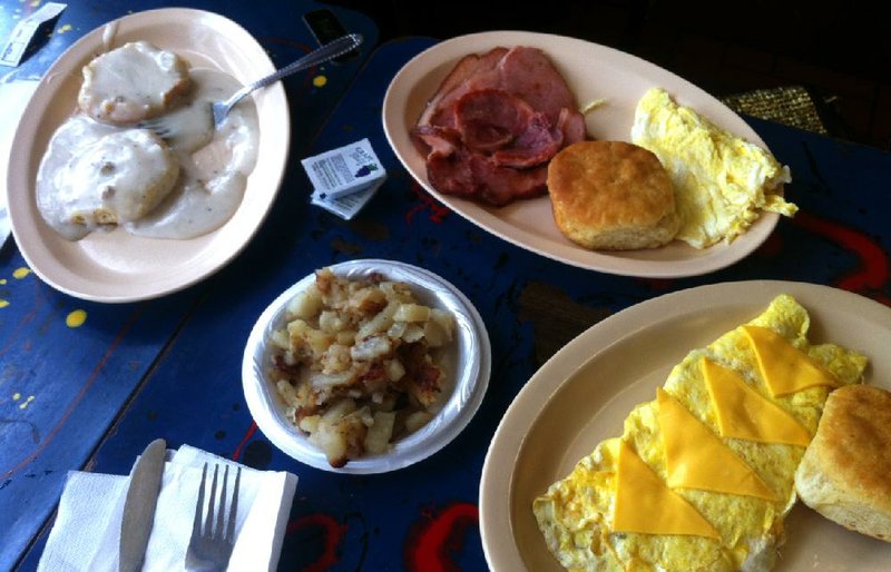 Breakfast offerings at David Family Kitchen include (clockwise from left): a biscuit smothered in sausage gravy, two eggs with a slab of salty ham and a vegetable omelet with a side of potatoes. 