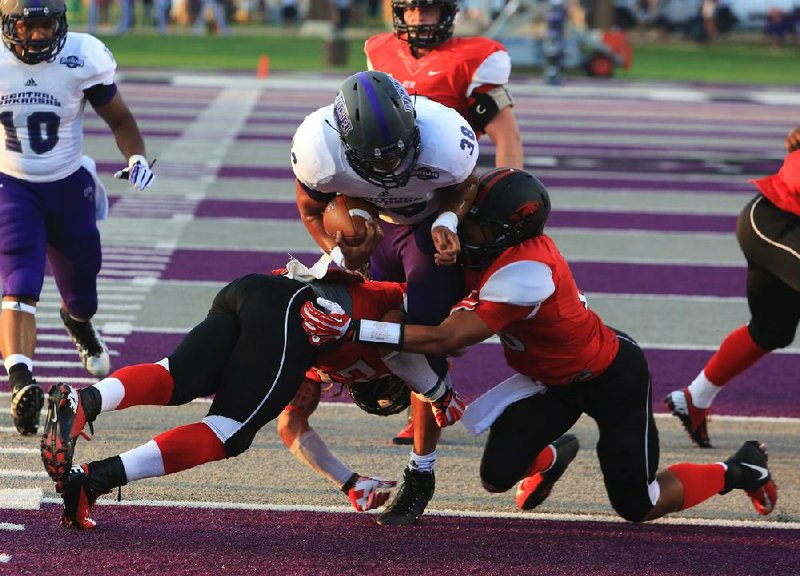 Arkansas Democrat-Gazette/RICK MCFARLAND --08/29/13--   UCA's Blake Veasley runs over two Incarnate Word defenders' Devin Haywood (left) and Tre Spragg for UCA's first touchdown during their game at Estes Stadium in Conway Thursday.


