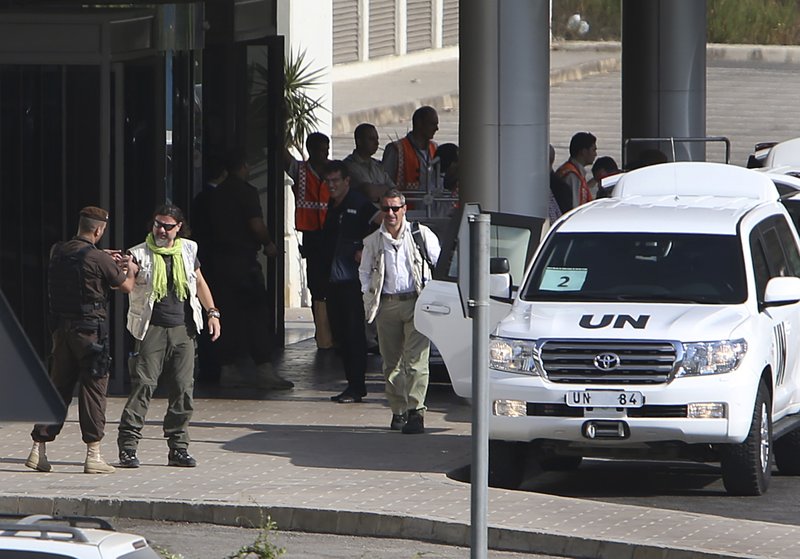 U.N. experts, second left, and center, arrive at the entrance of the private jet terminal at Beirut international airport, Lebanon, for the departure, after their convoy of U.N. experts left Syria into Lebanon on Saturday, Aug. 31. (AP Photo/Hussein Malla)