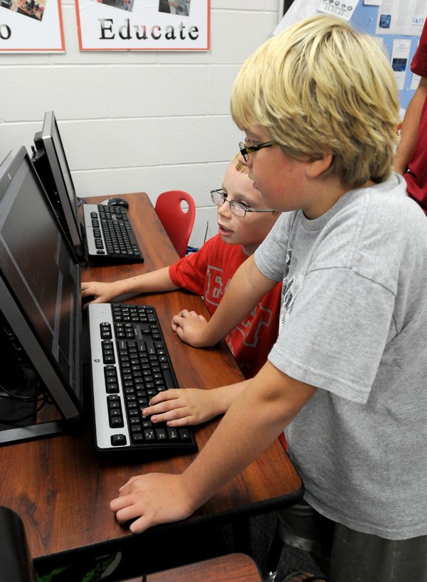 Jayden Eursery, 9, front, and Devin Gill, 9, both fourth grade students in EAST at Sonora Elementary School, look over code they worked on Friday, Aug. 30, 2013 at the school in Springdale. The pair and a few others in EAST are developing a smart phone app for the school.