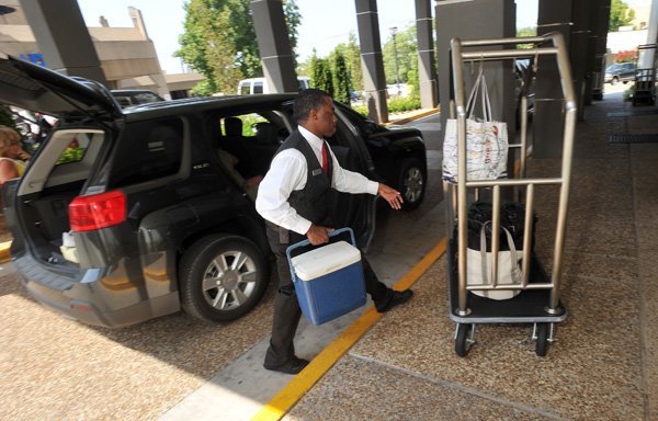 Tony Blackburn, Valet and Bellhop with the Chancellor Hotel in Fayetteville, helps a guest with their luggage as they check in Friday afternoon in Fayetteville.  Hotels are full for the Razorback's first game of the year. Occupancy rates for hotels in Benton and Washington counties was 53.5 percent through July this year and the Fayetteville occupancy rate was 47.3 percent.