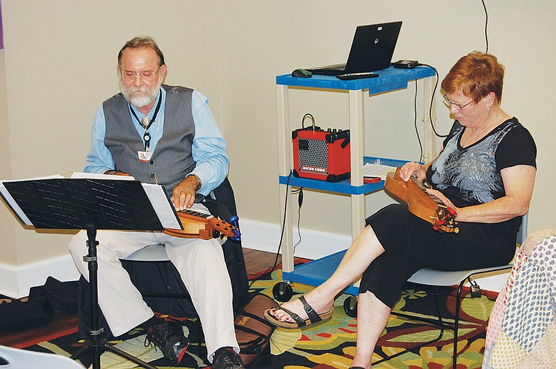 Dr. Terry Harville of Arkansas Children’s Hospital and the University of Arkansas for Medical Sciences Medical School, left, and mountain-dulcimer player and teacher Linda Brockinton play during a lecture and performance on music therapy and healing for an audience of around 30 people at the Mabel Boswell Memorial Library in Bryant on Friday. During the presentation, Brockinton played music, then slowed its tempo. Afterward, several members of the audience said the slower music lowered their heart rates.