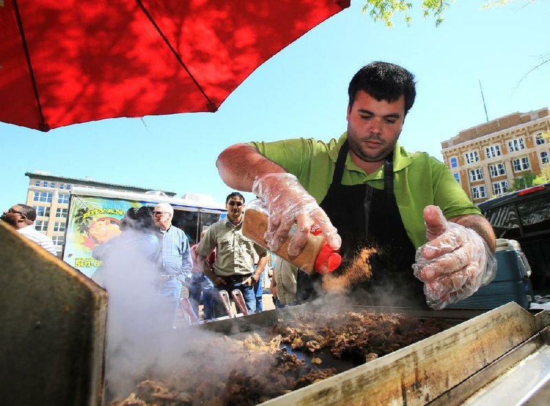 Joel Dunlap shakes spices onto steak sandwiches at his Philly’s Steak & Cheese cart, one of the vendors taking part in this week’s return of Food Truck Fridays in downtown Little Rock. 