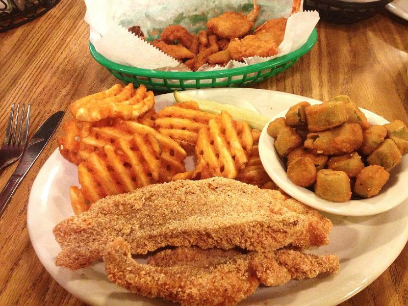 The Seafood Plate at Grampa’s is a two-dish affair that includes a basket of fried clam strips, a stuffed crab and three fried shrimp (background) and a plate with two catfish fillets and two sides — for example, waffle fries and fried okra. 
