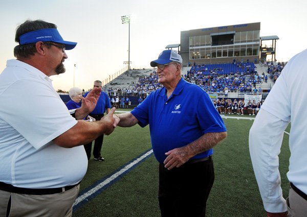 Whitey Smith, right, shakes hands with Rogers High defensive line coach Mike Bush during a dedication ceremony renaming the Rogers High stadium after Smith before the football game between Rogers High and Mountain Home on Friday September 6, 2013 in Whitey Smith Stadium in Rogers.