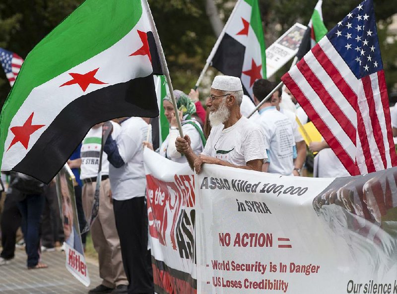 Waving the flag of the Syrian opposition, demonstrators opposed to the government of Syrian President Bashar Assad gather on the lawn of the Capitol in Washington, Monday, Sept. 9, 2013, as Congress returns to work from August recess. President Barack Obama is seeking authorization from Congress for a military strike against Syria in response to the use of chemical weapons in the civil war there. (AP Photo/J. Scott Applewhite)