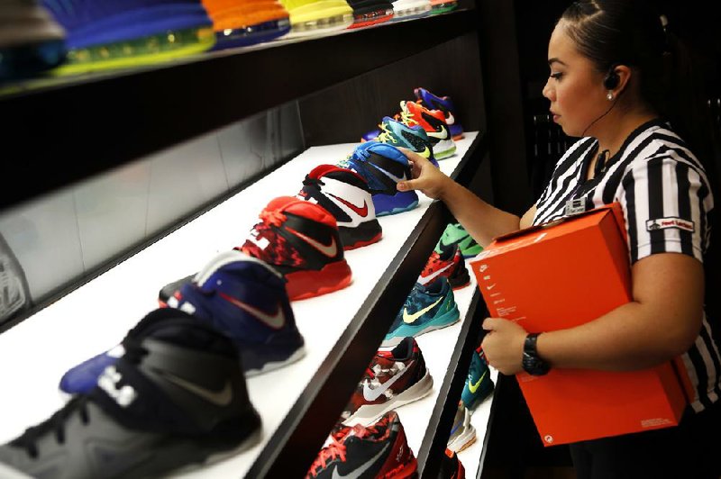 A Foot Locker employee arranges Nike basketball shoes last month at a store in Los Angeles. Nike Inc. is one of three companies that will be added to the Dow Jones industrial average Sept 23. 