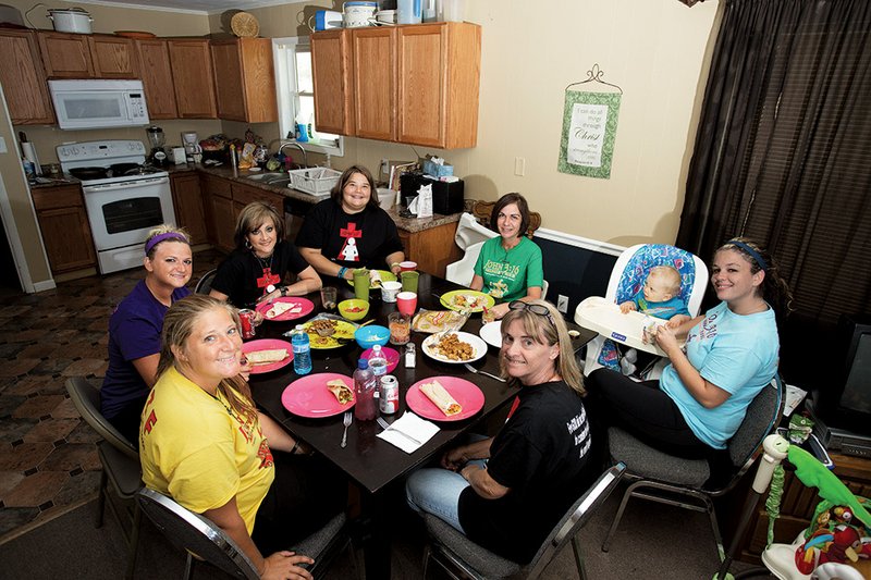The women at John 3:17 eat lunch before their daily Bible study. Shown, clockwise from bottom left, are Lindsay Cook, Destinee Pratt, Jenyi Eaton, Chelsea Dutton, Amy Ladd, Grady (Megan Roche’s son), Roche and Suzanne Rudd, facilitator of the John 3:17 program.
