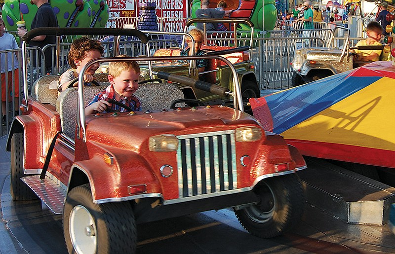 Children enjoy the illusion of driving in this kiddie ride at the Saline County Fair. The Saline and Hot Spring county fairs ended Saturday night, the fairs in Garland and Clark counties are going on now, and the Grant County fair will open Tuesday in Sheridan.