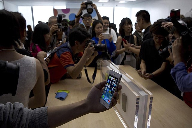 A journalist holds up an Apple Inc. iPhone 5S during a media event in Beijing on Wednesday. 