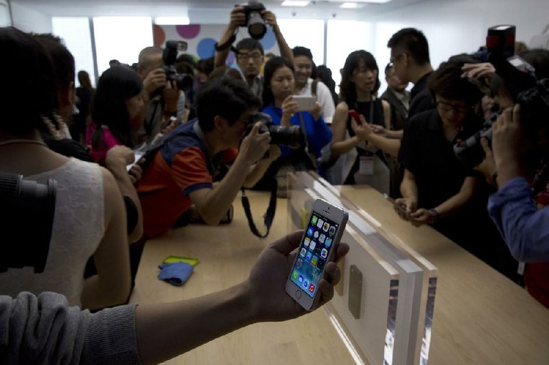A journalist holds up an Apple Inc. iPhone 5S during a media event in Beijing on Wednesday. 