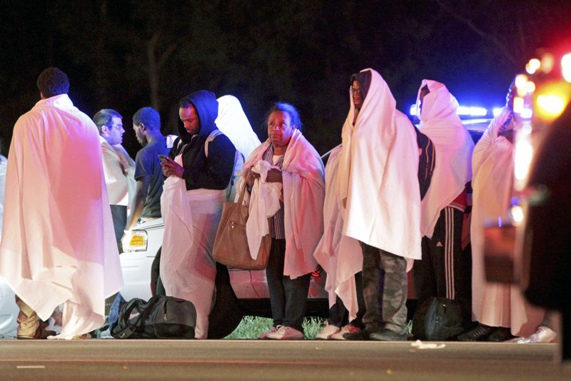Passengers of an overturned Greyhound bus stand near the scene, Saturday, Sept. 14, 2013, on interstate I-75 in Liberty Township, Ohio. Authorities say that at least 34 people have been hurt, with injuries ranging from minor to severe. (AP Photo/Dayton Daily News, Nick Daggy)