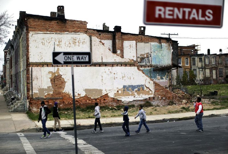 Boys walk past a collapsing row house in a desolate part of Baltimore in this April photo. The nation’s poverty rate was stagnant at 15 percent in 2012, census figures show, the sixth straight year the number has failed to improve. 