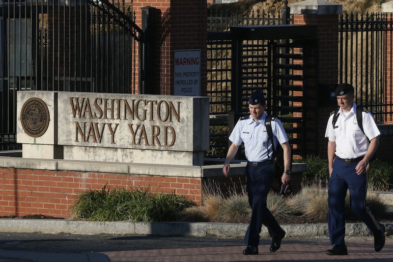 Military personnel walk past an entrance to the Washington Navy Yard Thursday, Sept. 19, 2013. The Washington Navy Yard began returning to nearly normal operations three days after it was the scene of a mass shooting in which a gunman killed 12 people. 