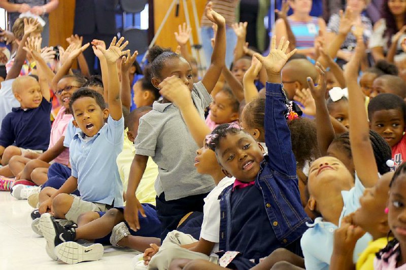 Pupils at Martin Luther King Jr. Elementary School raise their hands in support of reading during a kick-off event Sept. 16 for MLK Reads. The program is a partnership between Second Baptist Church and the school. 