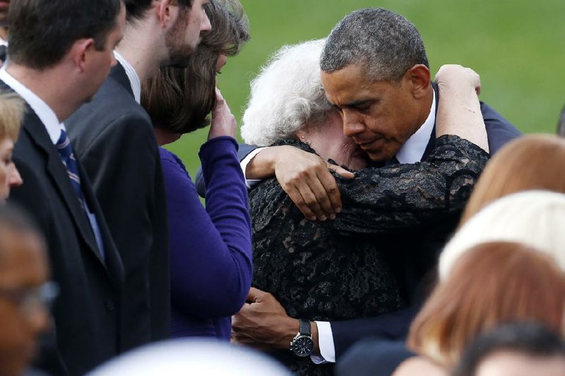 President Barack Obama comforts an unidentifed woman sitting in the family section at a memorial service for the victims of the Washington Navy Yard shooting at Marine Barracks Washington Sunday, Sept. 22, 2013.  A gunman killed 12 people in the Navy Yard on Monday, Sept. 16, 2013, before being fatally shot in a gun battle with law enforcement. The president and first lady Michelle Obama also visited with the victims' families. (AP Photo/Charles Dharapak)