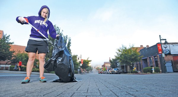 Grace Steiner, 16, a junior at Fayetteville High School and a musician in the school’s marching band, picks up trash on Dickson Street early Sunday after the Bikes, Blues & BBQ motorcycle rally that wrapped up Saturday.