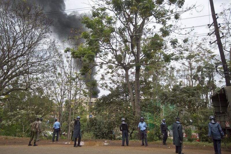 Kenyan police order bystanders and media away from an overlooking hill as a plume of black smoke billows over the Westgate Mall, following large explosions and heavy gunfire, in Nairobi, Kenya Monday, Sept. 23, 2013. Four large blasts rocked Kenya's Westgate Mall on Monday, sending large plumes of smoke over an upscale suburb as Kenyan military forces sought to rescue an unknown number of hostages held by al-Qaida-linked militants.