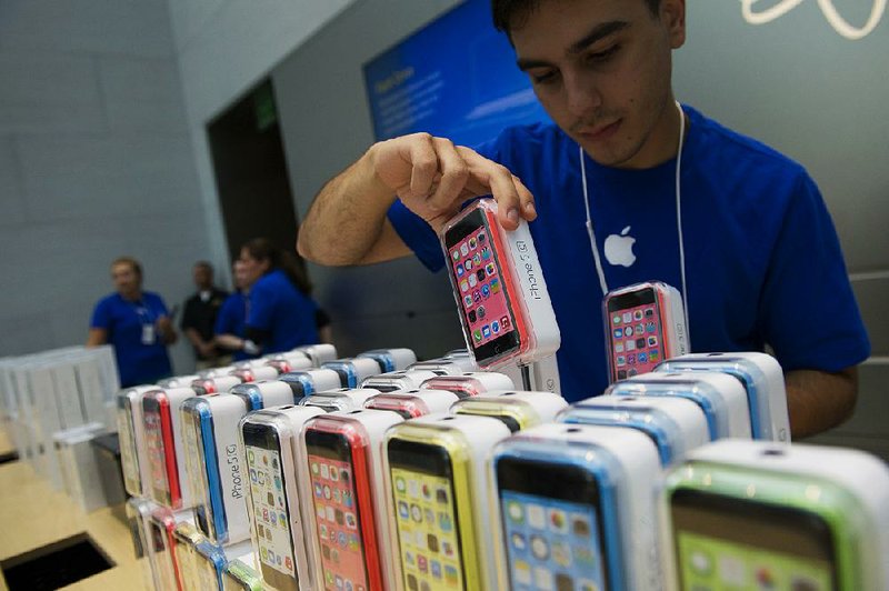 An employee arranges Apple Inc. iPhone 5c and 5s devices during the launch at the company's new store in Palo Alto, California, U.S., on Friday, Sept. 20, 2013. Apple Inc. attracted long lines of shoppers at its retail stores today for the global debut of its latest iPhones, in the company's biggest move this year to stoke new growth. Photographer: David Paul Morris/Bloomberg 
