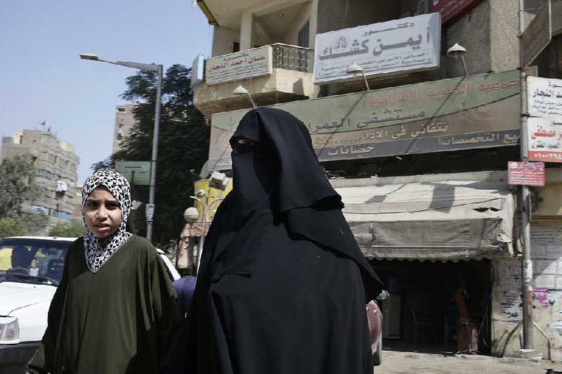 In this Saturday, Sept. 21, 2013 photo, an Egyptian woman and her daughter walk in front of Al-Omraniyah hospital, run by the Muslim Brotherhood's Islamic Medical Association, in Cairo, Egypt. An Egyptian court ordered a ban of the Muslim Brotherhood and confiscation of its assets Monday, Sept. 23, 2013, opening the door for authorities to dramatically accelerate a widescale crackdown. Egypt’s military-backed leaders have gone beyond arresting the group’s leaders to try to strike a more longterm blow, targeting its extensive network of schools, hospitals, mosques and other social institutions that made it the country’s strongest political power. (AP Photo/Hassan Ammar)