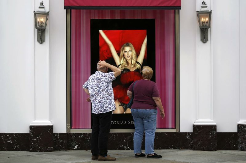 Shoppers stop to watch a video display outside a Victoria’s Secret Stores LLC location at Easton Town Center in Columbus, Ohio, on Friday. The Conference Board’s measure of consumer confidence fell in September to a four-month low. 