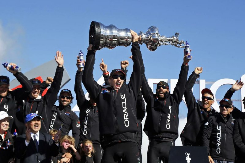 Oracle Team USA skipper Jimmy Spithill holds up the Auld Mug as the team celebrates Wednesday’s victory. 