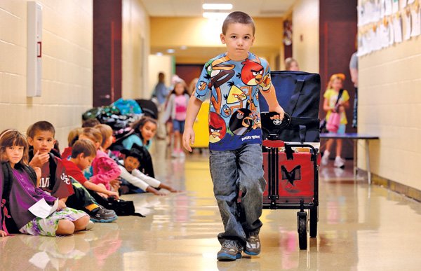 Gage Lautzenheiser, a Jones Elementary School first-grader, pulls a breakfast cart Wednesday down the hall to his classroom at the Bentonville school.