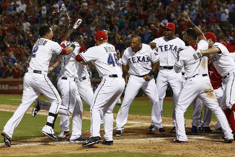 Texas Rangers' Jurickson Profar, second from left, arrives home to teammates celebrating his walk-off home run off Los Angeles Angels relief pitcher Michael Kohn during the ninth inning of a baseball game, Thursday, Sept. 26, 2013, in Arlington, Texas. The Rangers won 6-5. (AP Photo/Jim Cowsert)