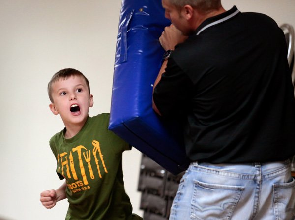 Jacob Sanchez, 9, strikes a pad held by Benton County Capt. Chris Sparks during a RADKIDS program on Thursday, Sept. 26, 2013, inside the Center for Nonprofits in Rogers. RADKIDS is a self-defense/self-esteem program for children in foster care.