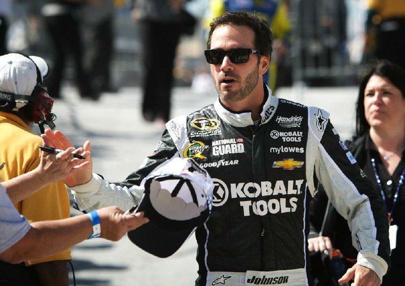 Jimmie Johnson gives a high-five to a fan as he arrives on pit road before the NASCAR Sprint Cup auto race in Dover, Del., Sunday, Sept. 29, 2013. Johnson won the race. (AP Photo/The News-Journal, Suchat Pederson) NO SALES