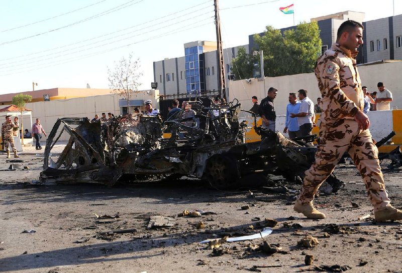 Security forces and citizens inspect the site of a car bomb attack in front of the main security forces headquarters in Irbil, Iraq, 350 kilometers (217 miles) north of Baghdad, Sunday, Sept. 29, 2013. A twin suicide car bombing and ensuing firefight in the capital of Iraq's largely peaceful self-ruled northern Kurdish region killed and wounded dozens of security forces on Sunday, officials said. (AP Photo)