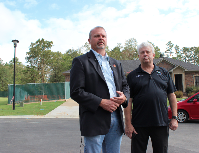 Faulkner County Judge Allen Dodson, left, and Mayflower Mayor Randy Holland speak Monday in front of the site where oil spilled from a pipeline in Mayflower about six months ago. The rupture site, to the left of the home, has been fenced off.