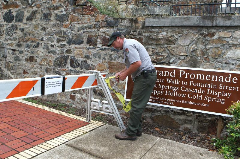 Park employee John Goy places yellow tape near a barricade while closing the Grande Promenade Tuesday in Hot Springs National Park.