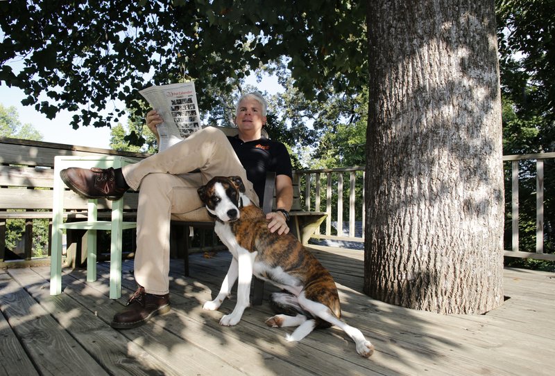 Rolf Wilkin sits with his dog Tuesday October 1, 2013 at his favorite personal space, the back deck of his Fayetteville home covered a tulip poplar tree.