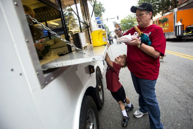 Gina Bailey gets a corn dog from Garrett's Funnel Cakes & More at the Main Street Food Truck Festival in downtown Little Rock while Aidan Bailey waits for his order of cotton candy Oct. 5, 2013. 