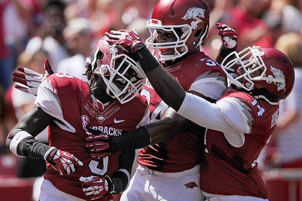 Arkansas defenders Eric Bennett, from right, and Braylon Mitchell celebrate with cornerback Will Hines intercepted a Southern Miss pass in the second quarter of the game in Razorbacks Stadium in Fayetteville on Saturday September 14, 2013.