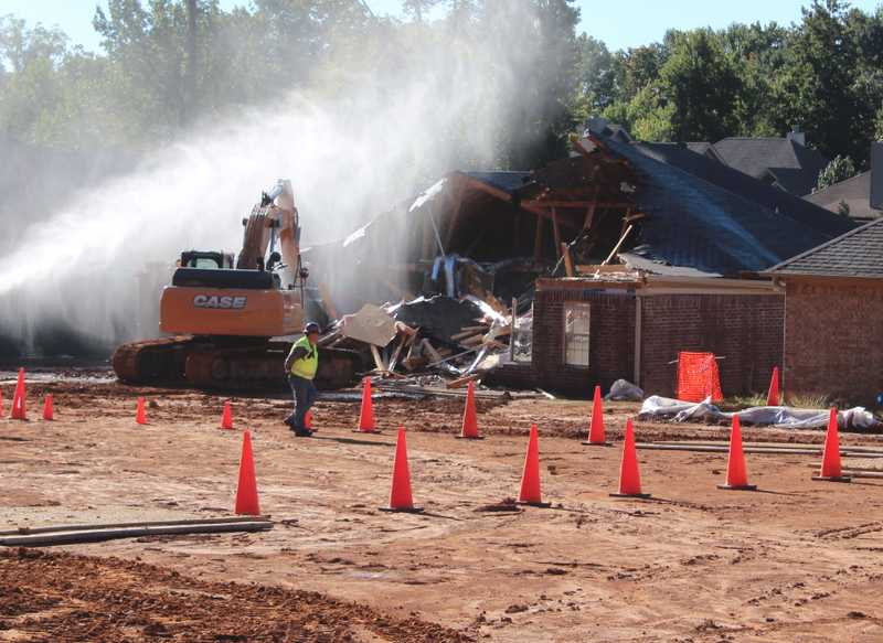 A backhoe works Monday to demolish a home near the site of the Mayflower oil spill.