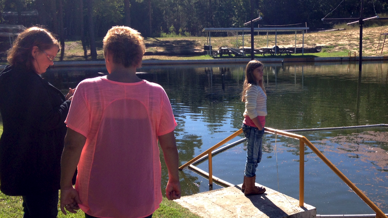 Kali Hardig looks out into the lake at Willow Springs Water Park, her first visit to the park since contracting a near-fatal brain-eating amoeba this summer. Her mother Traci (in pink) and the park's co-owner, Lou Ann Ratliff, look on behind her. 