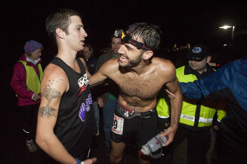 RYAN MCGEENEY/Arkansas Democrat-Gazette --10-06-2013-- Brock Hime of Little Rock, left, winner of the Arkansas Traveler 100, is greeted by 2nd-place finisher Wesley Hunt, also of Little Rock, shortly after both cross the finish line early Sunday morning. Brock crossed the finish line shortly after midnight with an official time of 18 hours, five seconds and 34 seconds. Hunt followed with an official time of 18 hours, six minutes and 42 seconds. The weekend's race was the first 100-mile competition for both of the men.