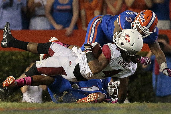 Keon Hatcher is tackled by Florida defenders Vernon Hargreaves III and Antonio Morrison during the third quarter of the Razorbacks game in Florida.