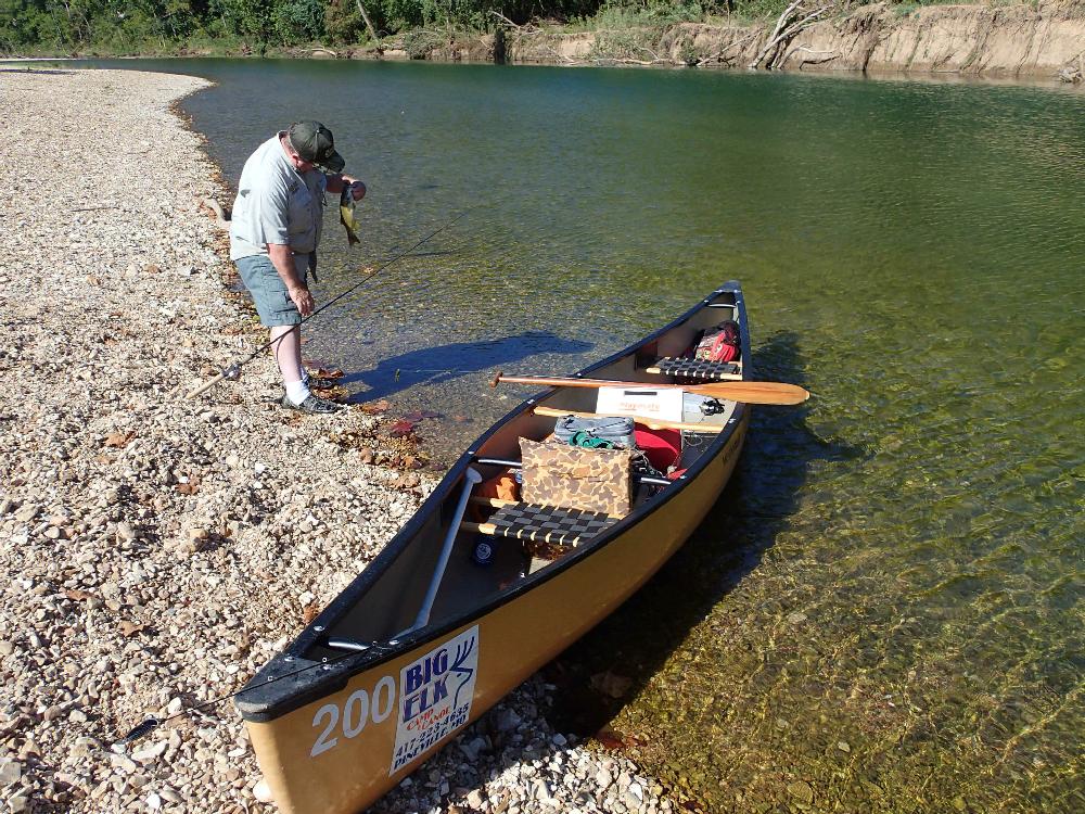 Duncan looks at a smallmouth bass he caught during a break to wade-fish.